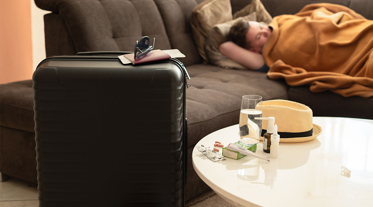 Een man ligt ziek op bed, terwijl hij op vakantie zou gaan.