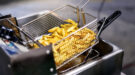 Close,Up,French,Fries,Potatoes,Cooking,In,Basket,Of,Frying