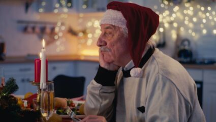 Een man die alleen aan de kersttafel zit.