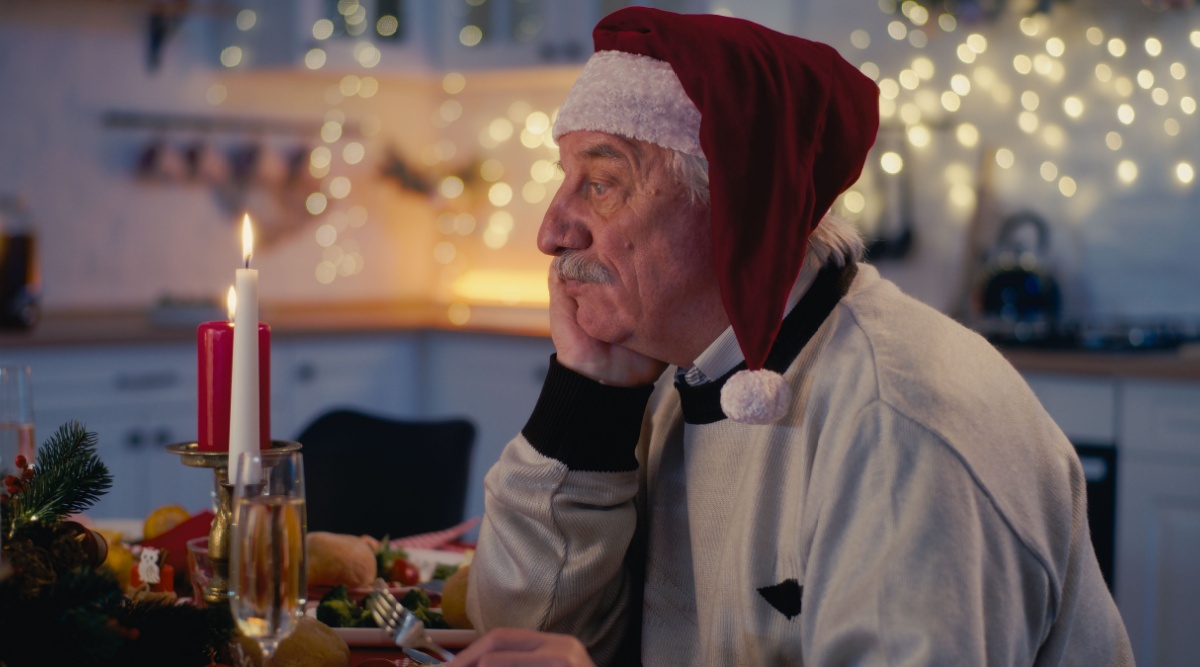 Een man die alleen aan de kersttafel zit.