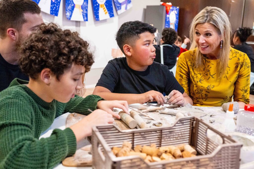 Koningin Máxima met kinderen aan een tafel met spullen voor muziek