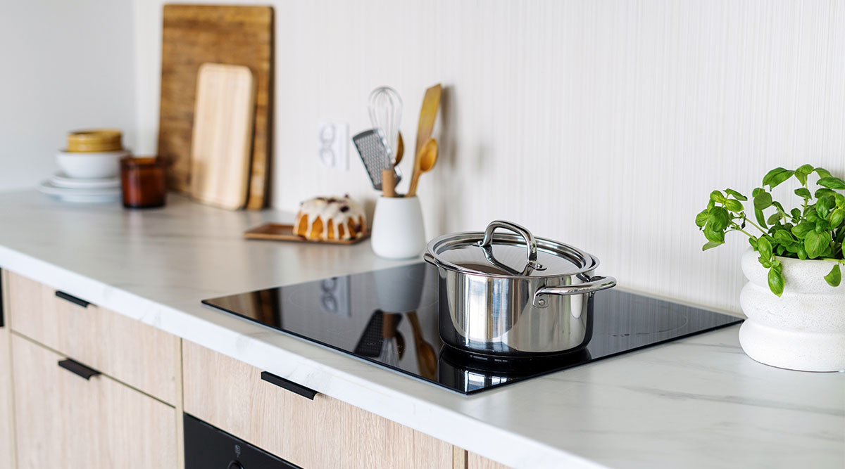 Een pan met deksel staat op een kookplaat in de keuken. Dit kan zowel keramisch al inductie zijn.