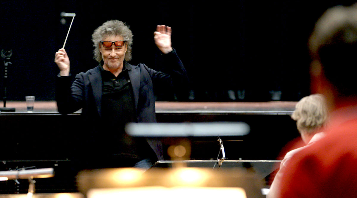 Dirigent Maurice Luttikhuis staat voor een orkest.