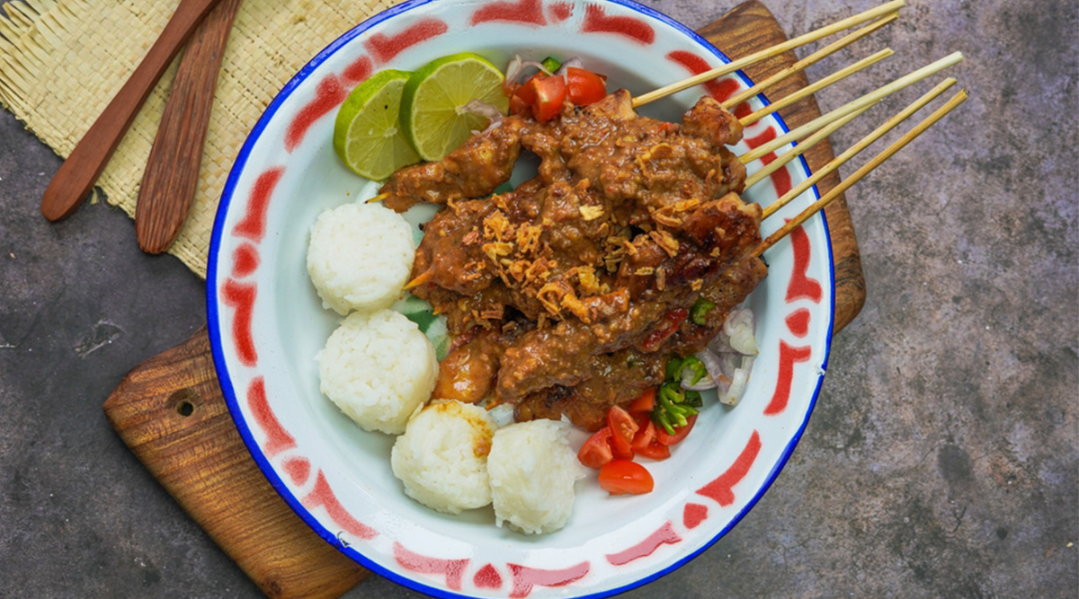 Pindasaus over een aantal stokjes met saté.