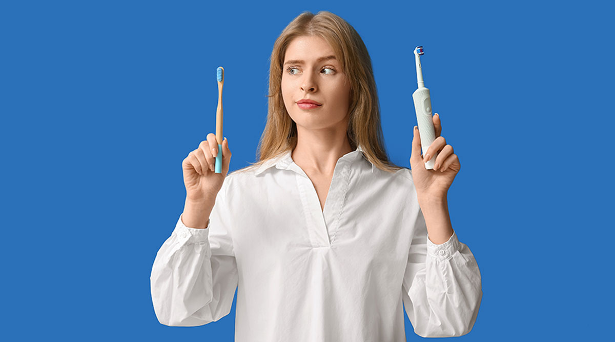 vrouw houdt een handtandenborstel en elektrische tandenborstel vast