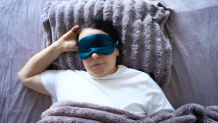 Vrouw ligt in bed met een verzwaringsdeken.