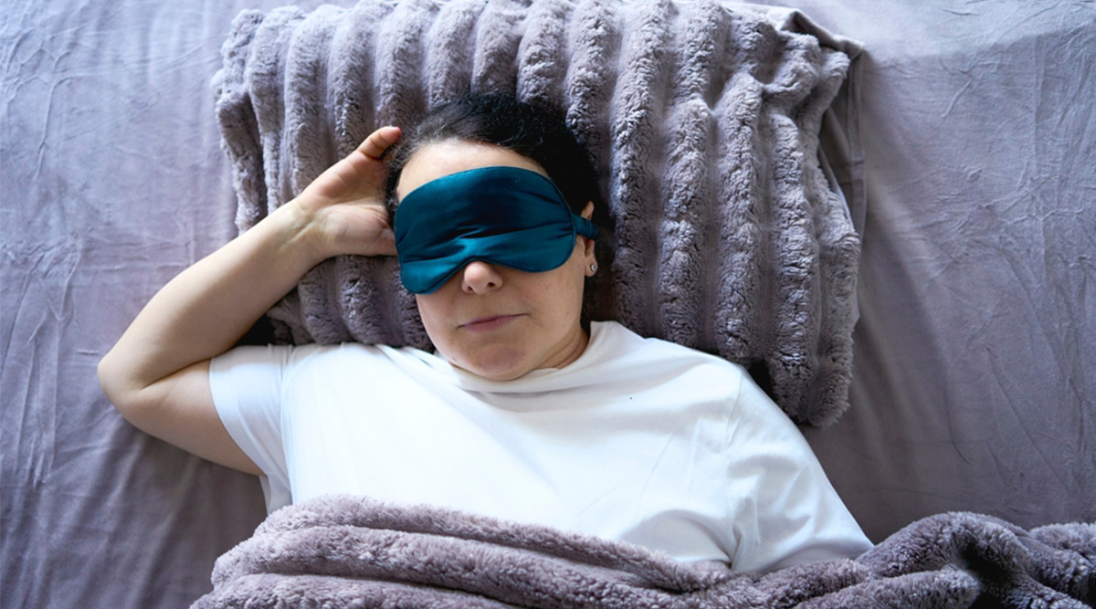 Vrouw ligt in bed met een verzwaringsdeken.