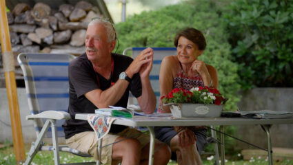 Reisleiders Ger en Evelyne Timmer zitten aan een campingtafel.