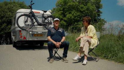 Rob en Martine van Os zitten op een campingstoel voor de caravan.