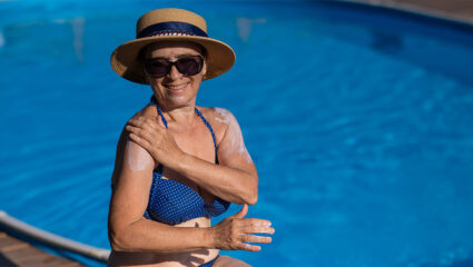 Dame aan het zwembad smeert zich in met zonnebrand.