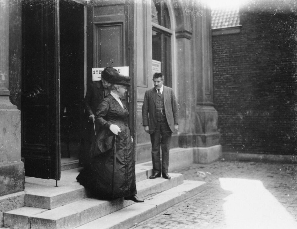 Koningin Emma (1858-1934) verlaat het stemlokaal, na te hebben gestemd voor de 2e kamer verkiezingen, woensdag 5 juli 1922