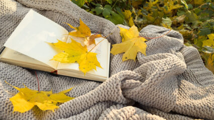 Een gehaakte deken met herfstbladeren.