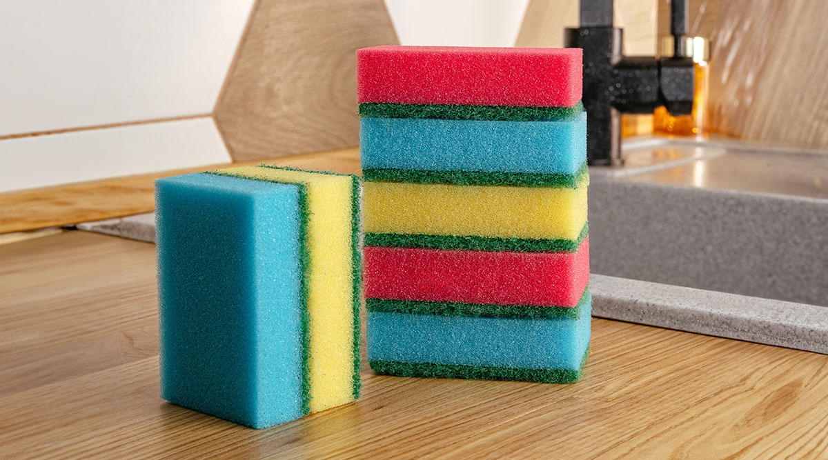Verschillende gekleurde schuursponsjes op een aanrechtblad in de keuken.