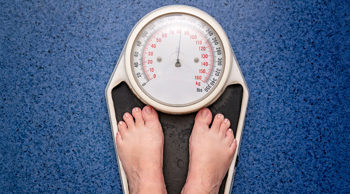 Beeld van een persoon, waar alleen de voeten van zichtbaar zijn, op een weegschaal.