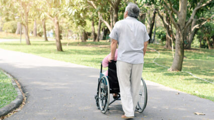 Oudere man en zijn vrouw die in een rolstoel zit. Theo en Gerda.