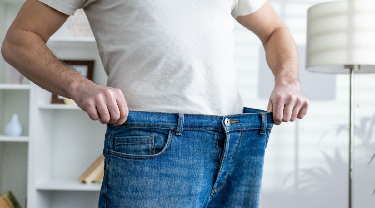 Een man die een te grote broek aanheeft.