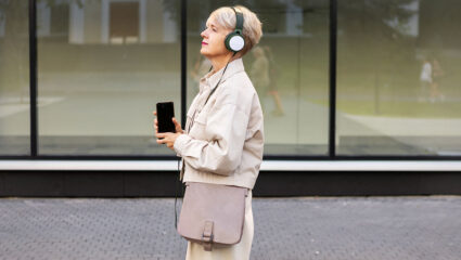 Een vrouw loopt met een koptelefoon op en met een telefoon in de hand rond. Net zoals bij een podwalk.