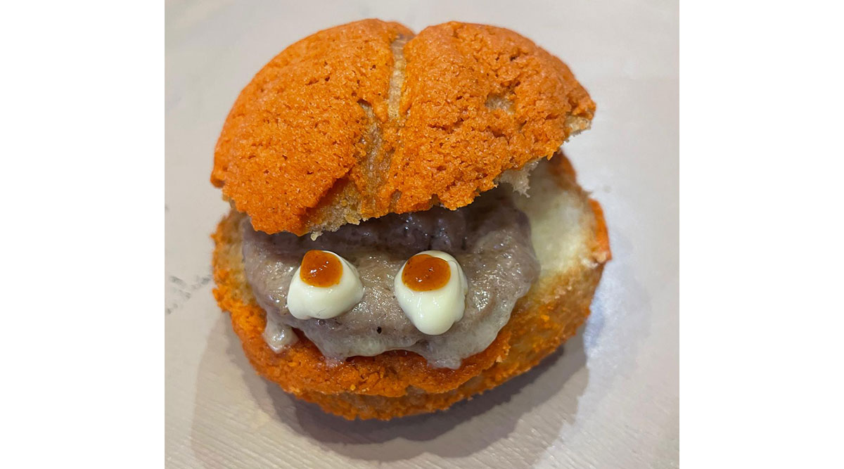 Een pompoenbroodje met een hamburger erin.