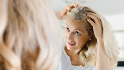 Mevrouw bekijkt uitgroei in de spiegel.