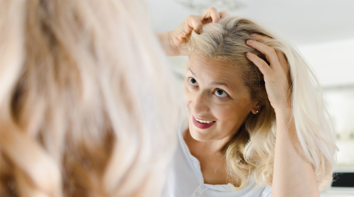 Mevrouw bekijkt uitgroei in de spiegel.