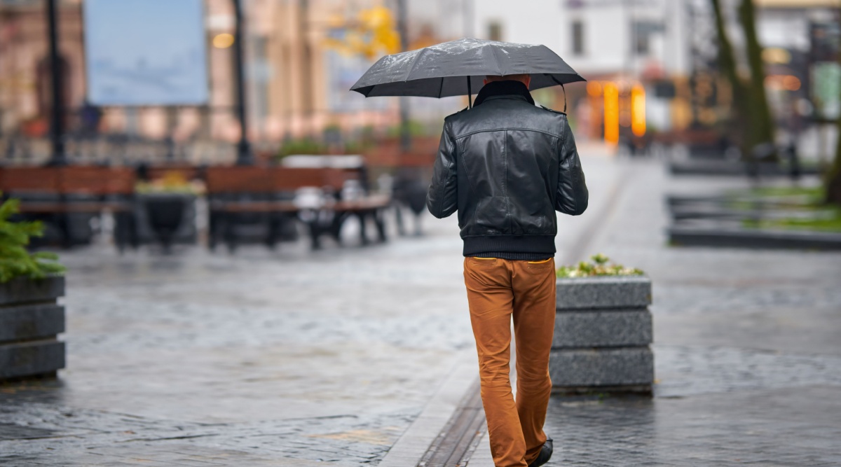 Iemand loopt in de regen met een paraplu.