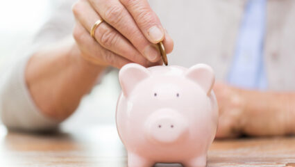 Mevrouw stopt geld in een spaarvarken.