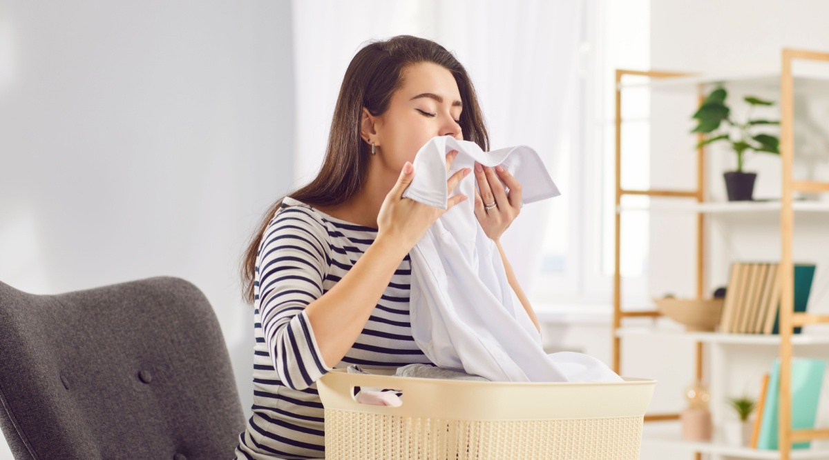 Iemand ruikt aan de was die ze net uit de wasmachine heeft gehaald.