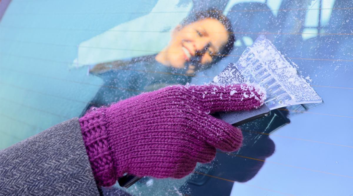 Mevrouw krabt de autoruit waar ijs op zit.
