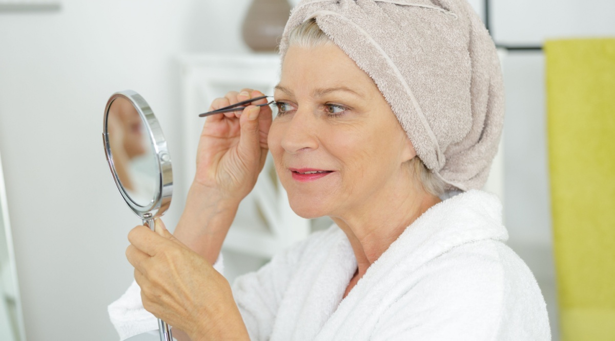 Een vrouw epileert haar wenkbrauwen.