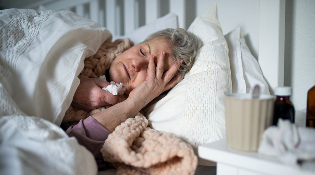 Een mevrouw ligt verkouden in bed.