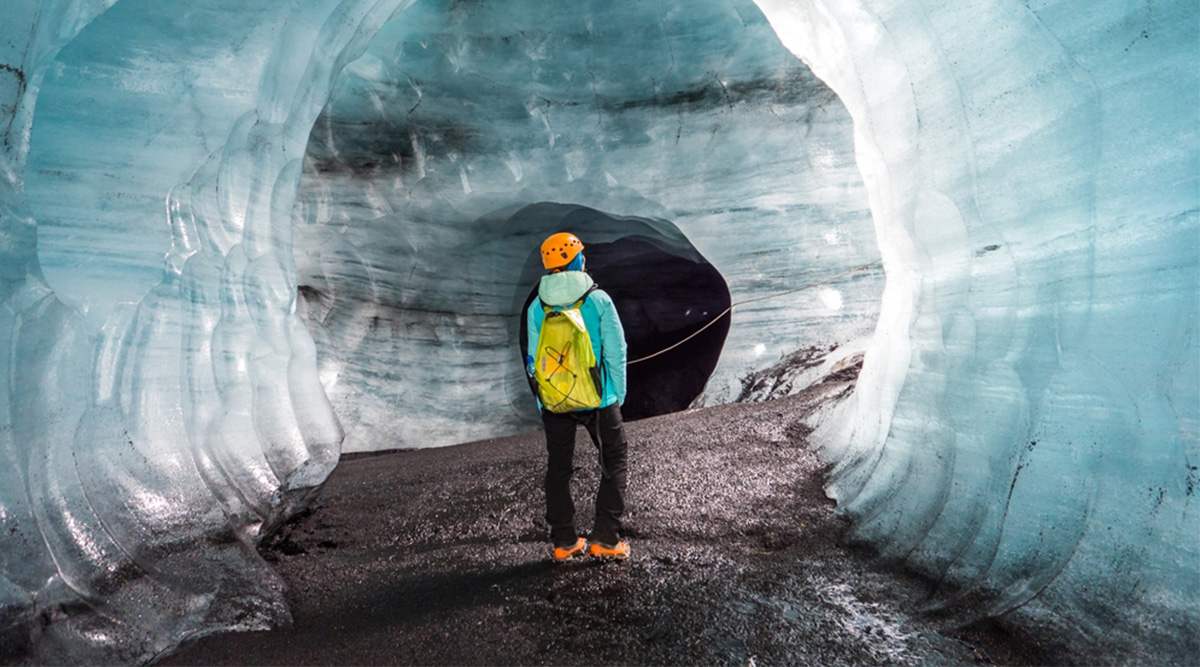 meneer staat in een ijsgrot in IJsland.