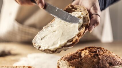 Iemand smeert smeerkaas op haar brood.