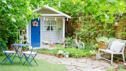 Een wit tuinhuisje met een blauwe deur.