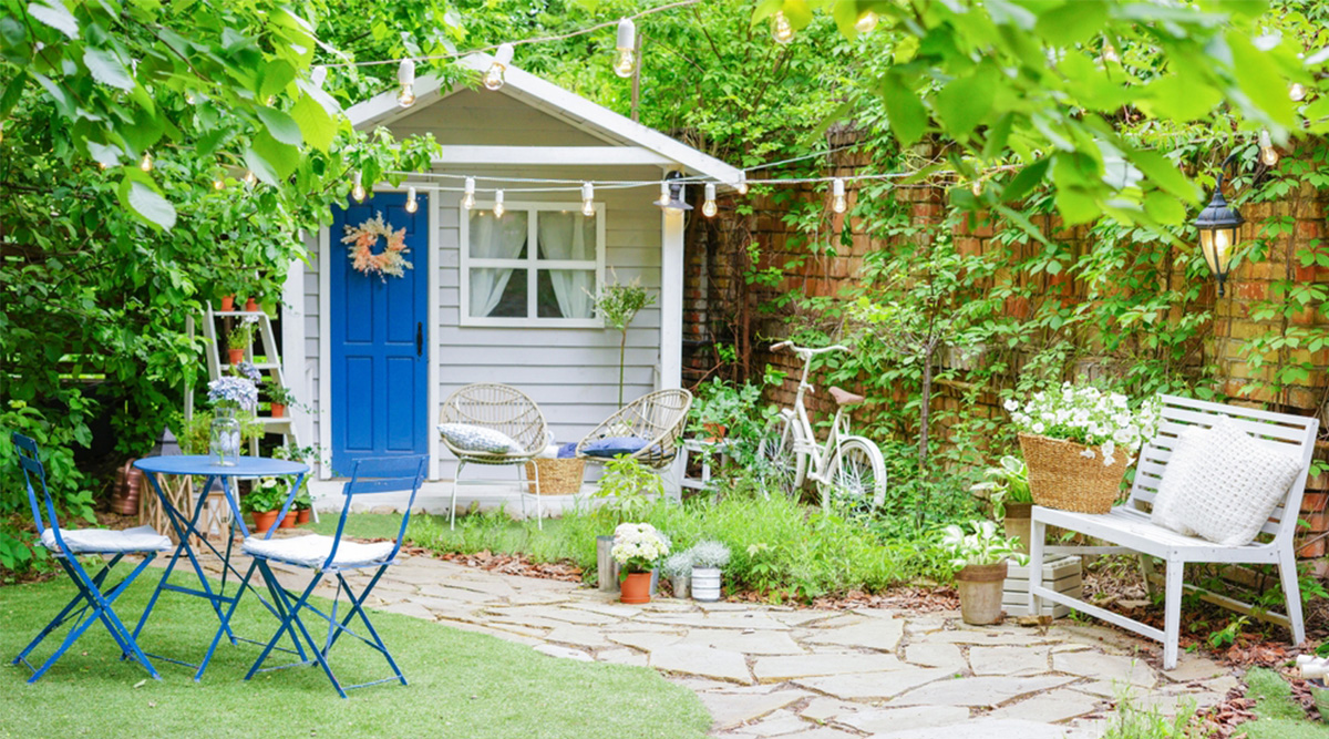 Een wit tuinhuisje met een blauwe deur.