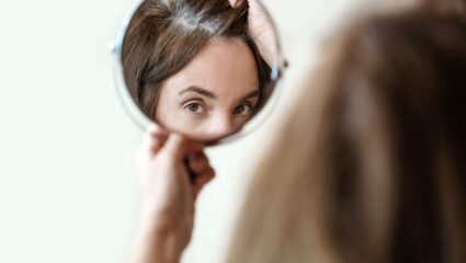 Vrouw kijkt in spiegel en ziet grijs haar