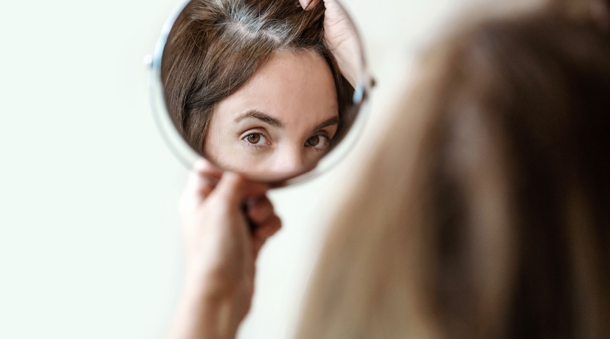 Vrouw kijkt in spiegel en ziet grijs haar
