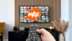 Een afstandsbediening met een tv vervaagt op de achtergrond met het MAX-logo.