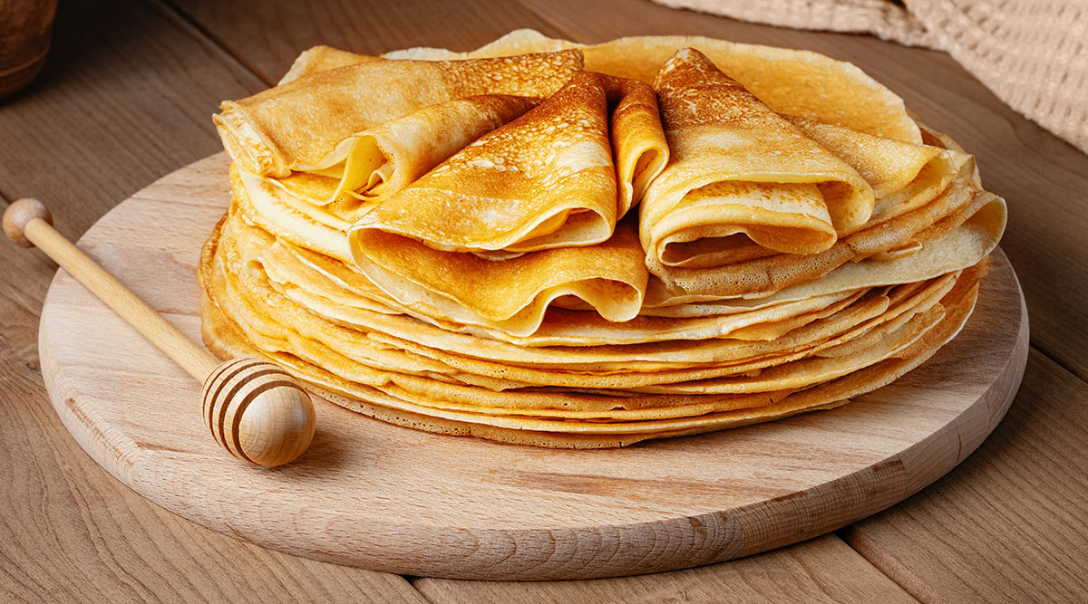 Een stapel crêpes op een houten plank.