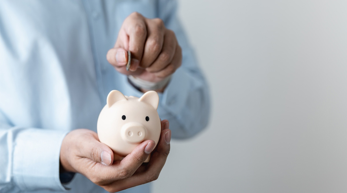 Iemand stopt geld in een spaarvarken om te besparen.