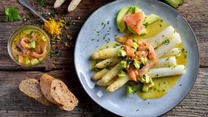 Witte asperges met zalm op een bord.