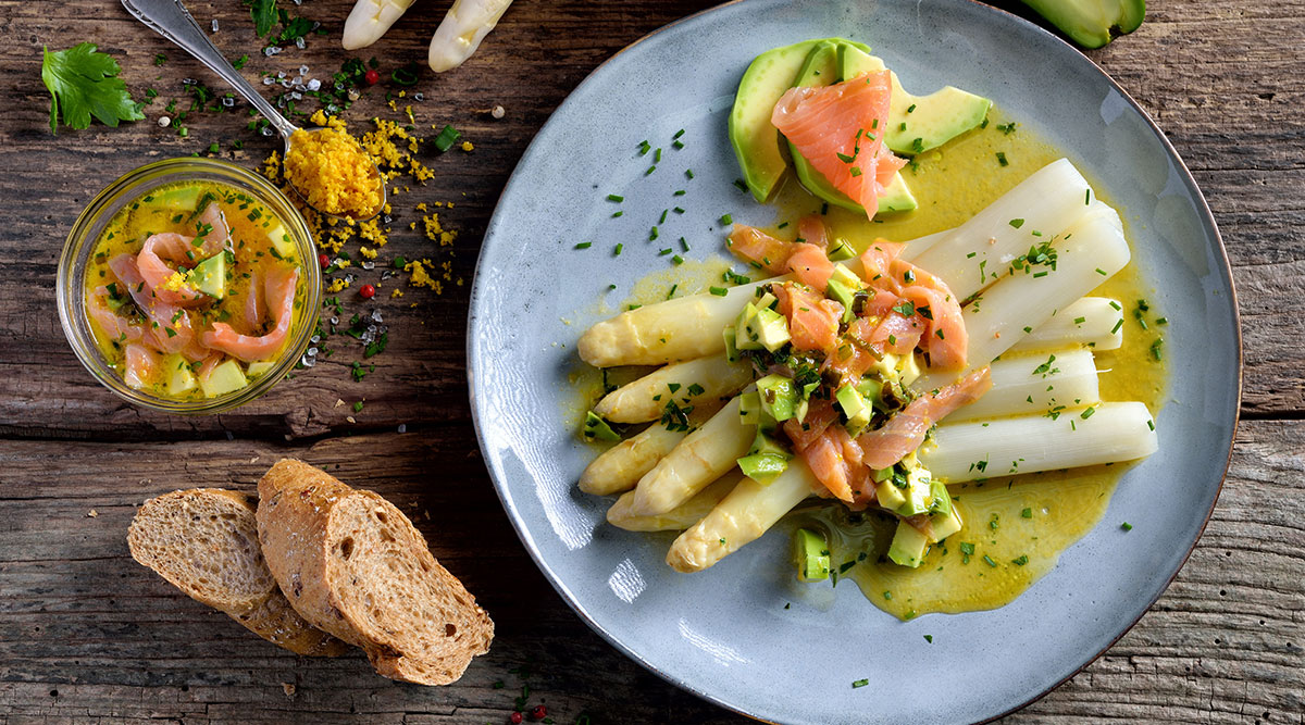 Witte asperges met zalm op een bord.