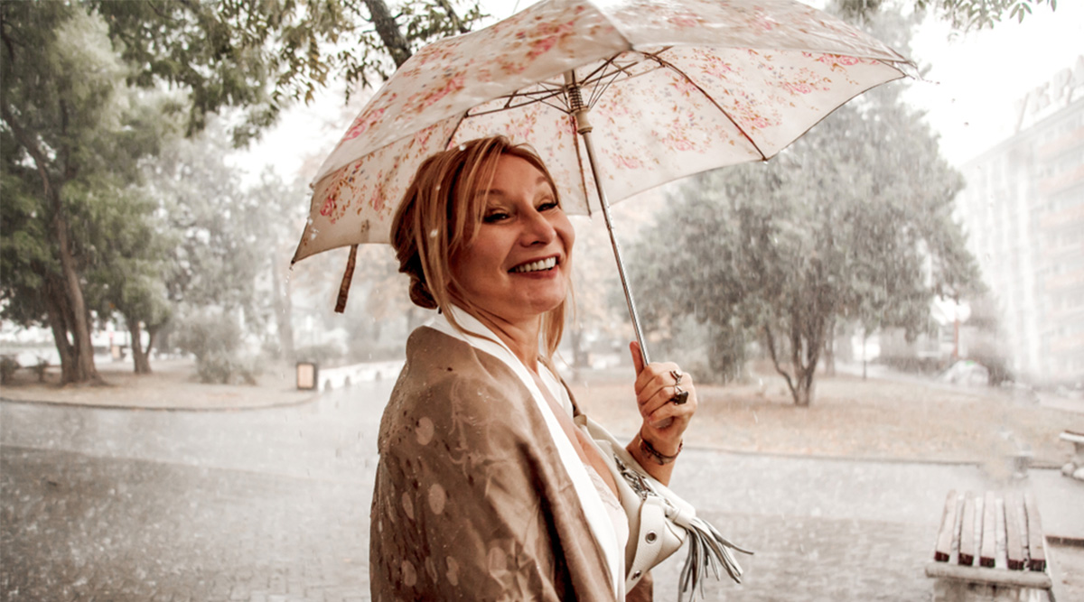 Mevrouw beschermt kapsel tegen de regen.