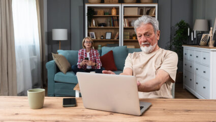 Een man achter een laptop en een vrouw op de bank, ze bespreken hun pensioengat.