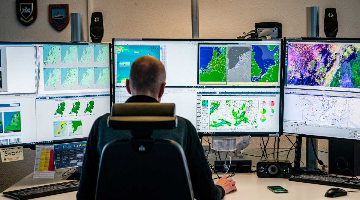 meteoroloog in de weerkamer van het KNMI achter zijn bureau