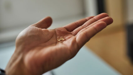 Een hand met daarop 2 pilletjes vitamine D.