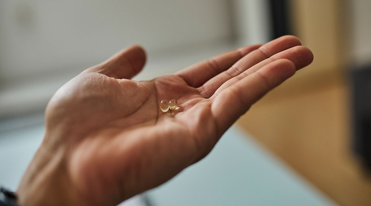 Een hand met daarop 2 pilletjes vitamine D.