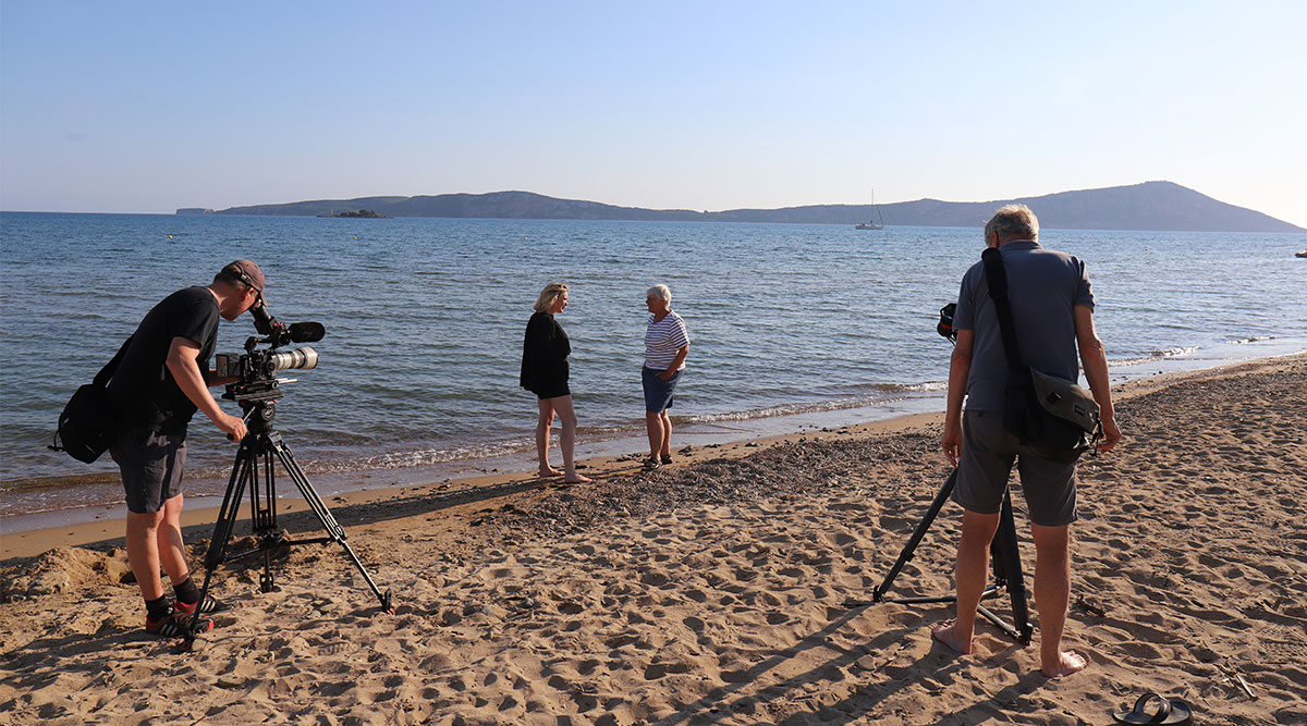 Marlijn en Rina op het strand, terwijl de crew filmt.