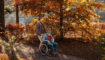 Een man in een rolstoel maakt een wandeling met zijn kleinzoon, in een herfstachtig bos.