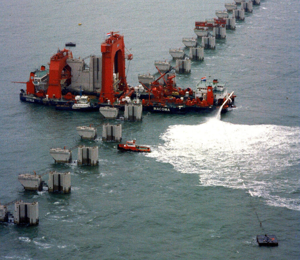 Met een speciaal schip worden de pijlers naar hun bestemming bij de de Oosterscheldekering vervoerd