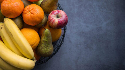 Een volle fruitschaal, met bananen, peren en mandarijnen.